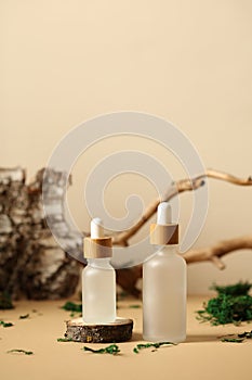 Transparent glass dropper bottles with natural serum. Tree branch, bark birch, moss on background