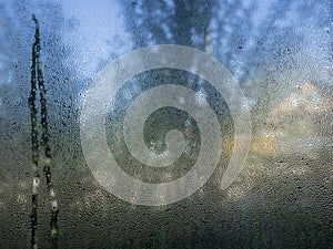 Transparent glass in drops of water. Misted window. Wet glass surface. Abstract background, texture for wallpaper