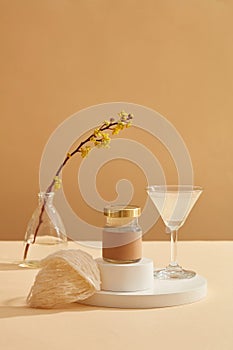 A transparent glass filled with bird nest soup standing next to a jar placed on podium,