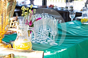 Transparent glass goblets next to a carafe of orange juice summer holiday