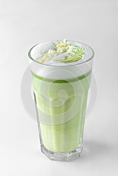 Transparent glass with green coffee latte, frothed milk, syrup, whipped cream and topping