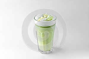 Transparent glass with green coffee latte, frothed milk, syrup, whipped cream and topping