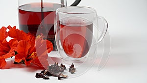 A transparent glass  with hot red carcade floral tea