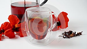 A transparent glass  with hot red carcade floral tea