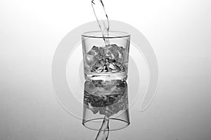 Transparent glass with ice in which vodka is poured