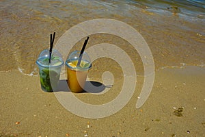 a glass of lemonade with a straw on the seashore, a sunny beach, summer vacation. background for the design.