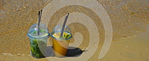 a glass of lemonade with a straw on the seashore, a sunny beach, summer vacation. background for the design.