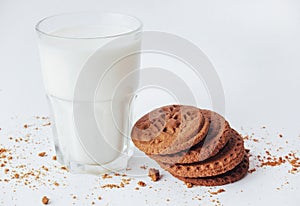 Transparent glass of milk and cookies on a white background