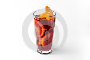 Transparent glass of red refreshing winter drink mulled wine with sliced orange isolated on a white and gray background with