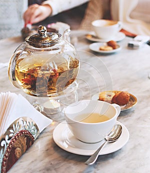 Transparent glass teapot with green tea on a table in a cafe, selective focus