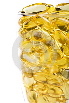 Transparent glass vessel with fish oil orange yellow softgels capsules fish oil omega 3 or omega 6, vitamin A, D, E isolated on