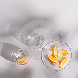 Transparent glasses of refreshing cold water with slices of lemon and ice on white background. Summer healthy drink