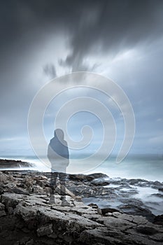 Transparent gloomy hooded man silhouette in a seascape