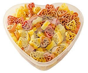 Transparent heart shape vase (bowl) filled with colored (red, yellow an orange) heart shape pasta, white background
