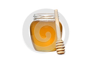 A transparent jar with honey and a wooden spoon stands on a white isolated background.