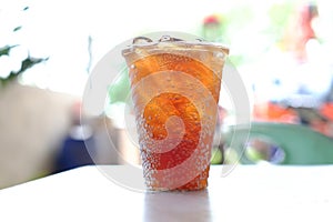 Transparent nectar, ice in a plastic cup, placed on a white table, soft background in natural light.