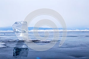 A transparent piece of ice on the surface of the blue frozen lake Baikal