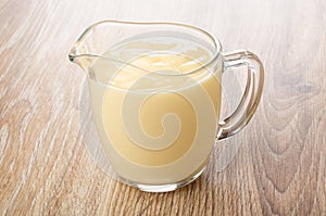 Transparent pitcher with yogurt on table