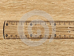 Transparent plastic school ruler on a wooden table. Millimeters and centimeters are marked in black. Measuring length and width photo
