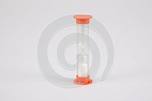 Transparent plastic timer hourglass with white sand for measuring time in grey background