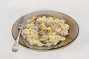 Transparent plate and fork with pasta spaghetti carbonara with cream, mushrooms, bacon