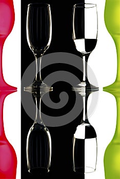 Transparent and the red-green wine glasses on the black-and-white background with reflection.