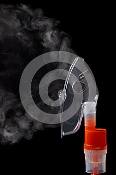 Transparent respiratory mask on atomizing cup with steam on black background