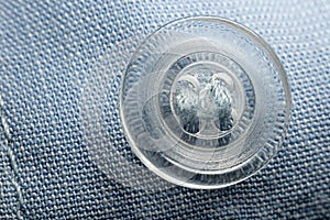 Transparent round button sewn to blue cloth