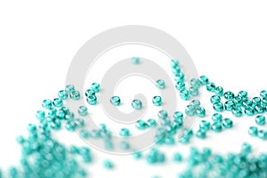 Transparent seed beads aquamarine color scattered on a white surface close-up