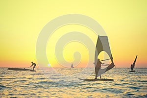 Transparent silhouettes of wind surfers at sunset