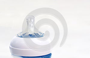 The transparent silicone teat of a blue baby bottle