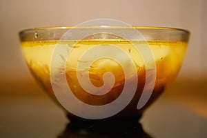 Transparent soup is in a bowl of dark glass