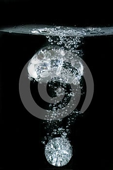 Transparent sphere, submerging in water, on black background