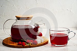 Transparent teapot and cup with red sweet tea with raspberries. Detox berries antioxidant home health drink. Copy space