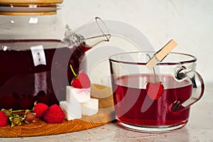 Transparent teapot and cup with red sweet tea with raspberries. Detox berries antioxidant home health drink. Copy space