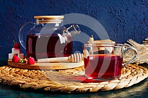 Transparent teapot and cup with red tea with raspberries and apples. Detox antioxidant home health drink. Copy space