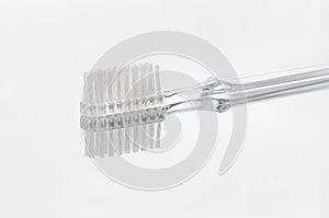 Transparent toothbrush with reflection on gray background selective focus