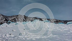 Transparent turquoise ice hummocks rise above the frozen lake.