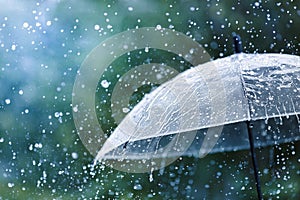 Transparent umbrella under rain against water drops splash background. Rainy weather concept photo