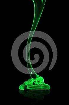 Transparent viscous green liquid flows on black background