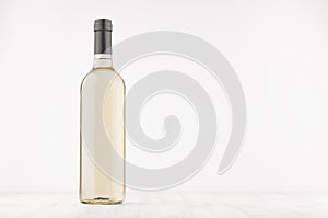 Transparent wine bottle with white wine on white wooden board, mock up.