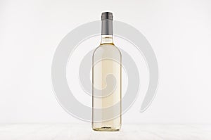 Transparent wine bottle with white wine on white wooden board, mock up.