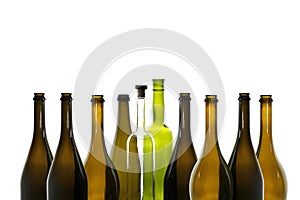 Transparent wine bottle with wine stopper and green wine bottle among brown empty wine bottles isolated on white b