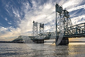 Transport arched truss drawbridge across the Columbia River against a cloudy sky at sunset