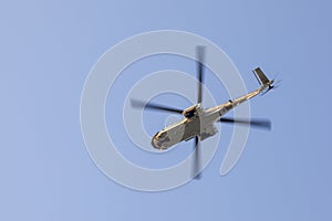 Transport helicopter in flight, with big propeller blades seen from below against Blue sky. Empty space for text.