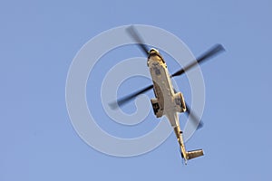 Transport helicopter in flight, with big propeller blades seen from below against Blue sky. Empty space for text.