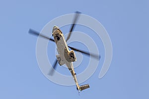 Transport helicopter in flight, with big propeller blades seen from below against Blue sky. Empty space for text.