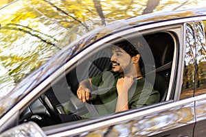 transport, safety and people concept. Happy smiling indian man or driver fastening seat belt in car