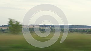 Transport, travel, road, railway, landscape, communication concept - view from window of speed train on landscape of yellow wheat