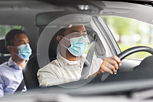 male driver in mask driving car with passenger